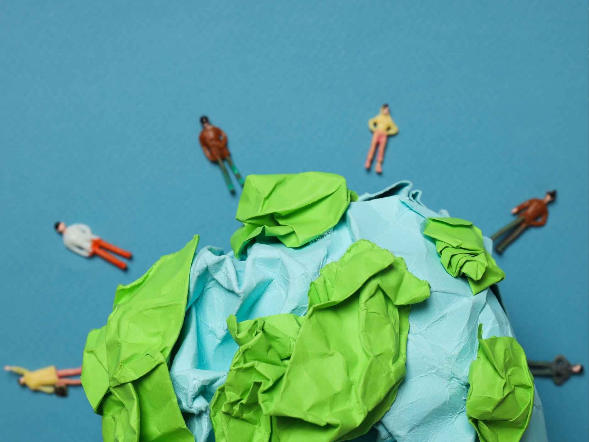 bola del mundo de papel, con muñecos alrededor sobre fondo azul