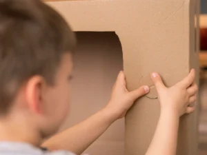 niño pegando piezas de cartón
